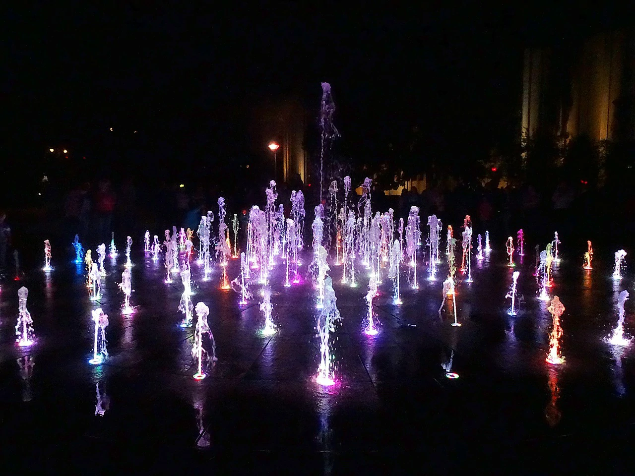 Plaza dancing fountain at night with interactive water effects and lighting for a public square