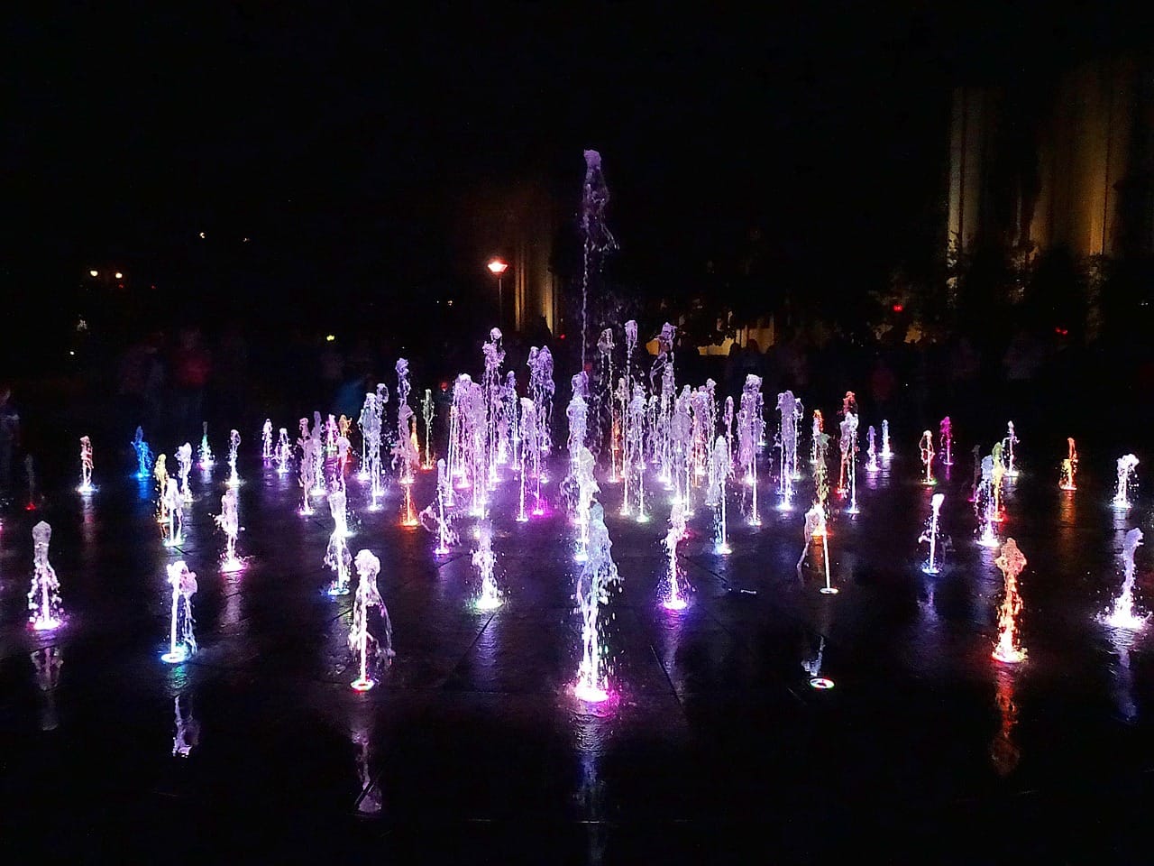 Plaza dancing fountain at night with interactive water effects and lighting for a public square