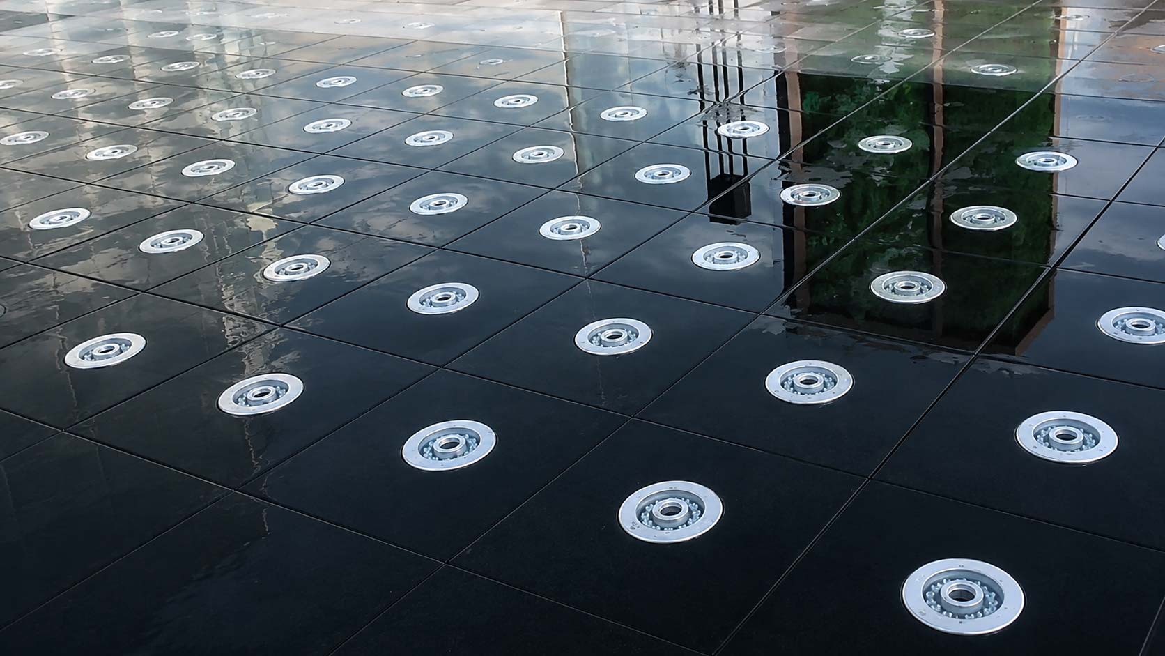 Dry deck fountain integrated with paving and surrounding architectural landscape