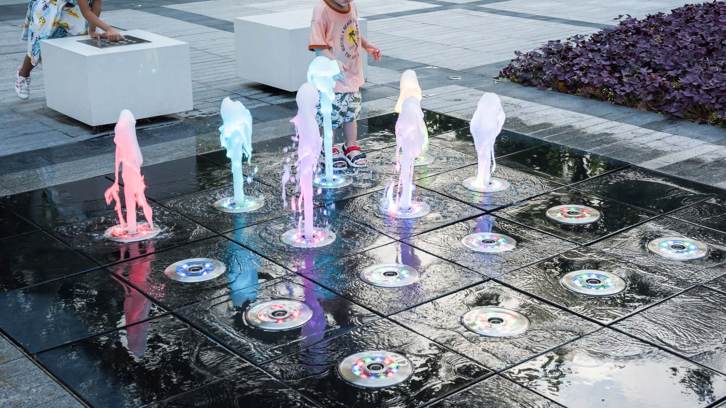 Interactive dry deck fountain with visitors walking among ground-level water jets