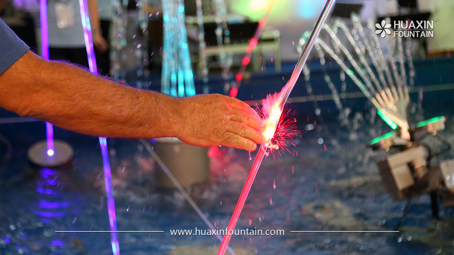 Visitor touching the water stream of a laser-illuminated laminar jet at the Canton Fair