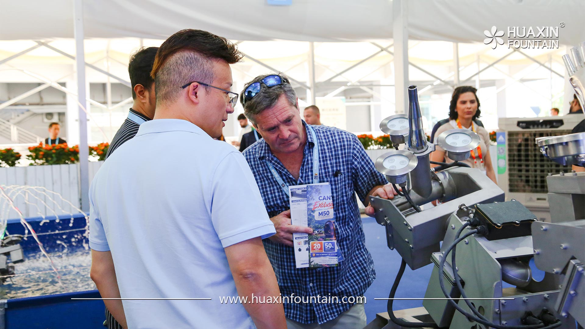 Visitors discussing fountain equipment with the Huaxin Fountain team at the exhibition